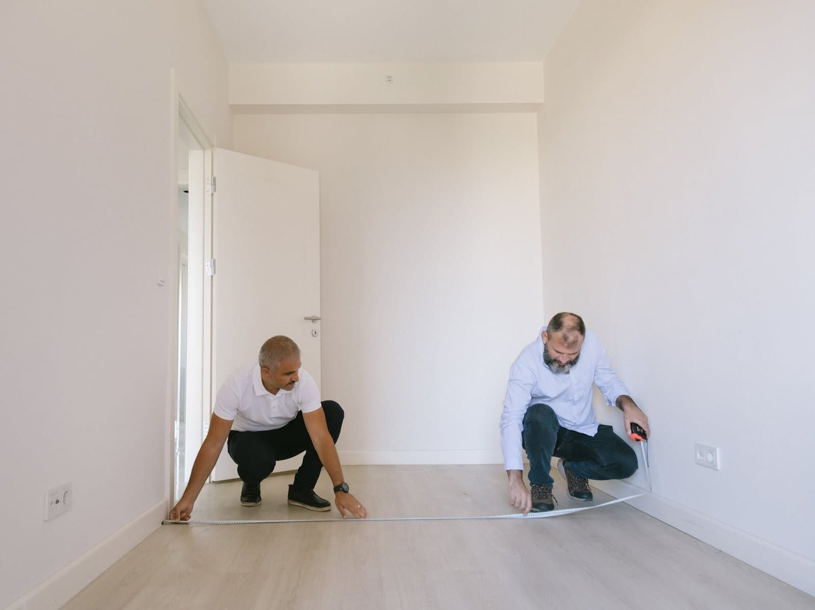 two men measuring length of the empty room with white walls rental property in Land O' Lakes